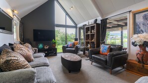 Un salon spacieux avec un plafond haut, une grande fenêtre et une vue sur l’extérieur.