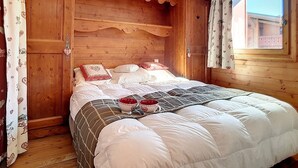 A wooden room with a bed, curtains, and a window. - Bright 3-room apartment with balcony, close to slopes (Les Menuires)