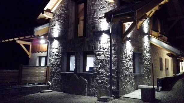 A stone building with a sloped roof and wooden beams, featuring a porch and a bench. - Duplex 5 rooms, 10 people, south, pets allowed, private parking (Valloire)