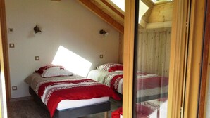 A bedroom with two beds, wooden beams, a skylight, and a glass door. - Duplex 5 rooms, 10 people, south, pets allowed, private parking (Valloire)