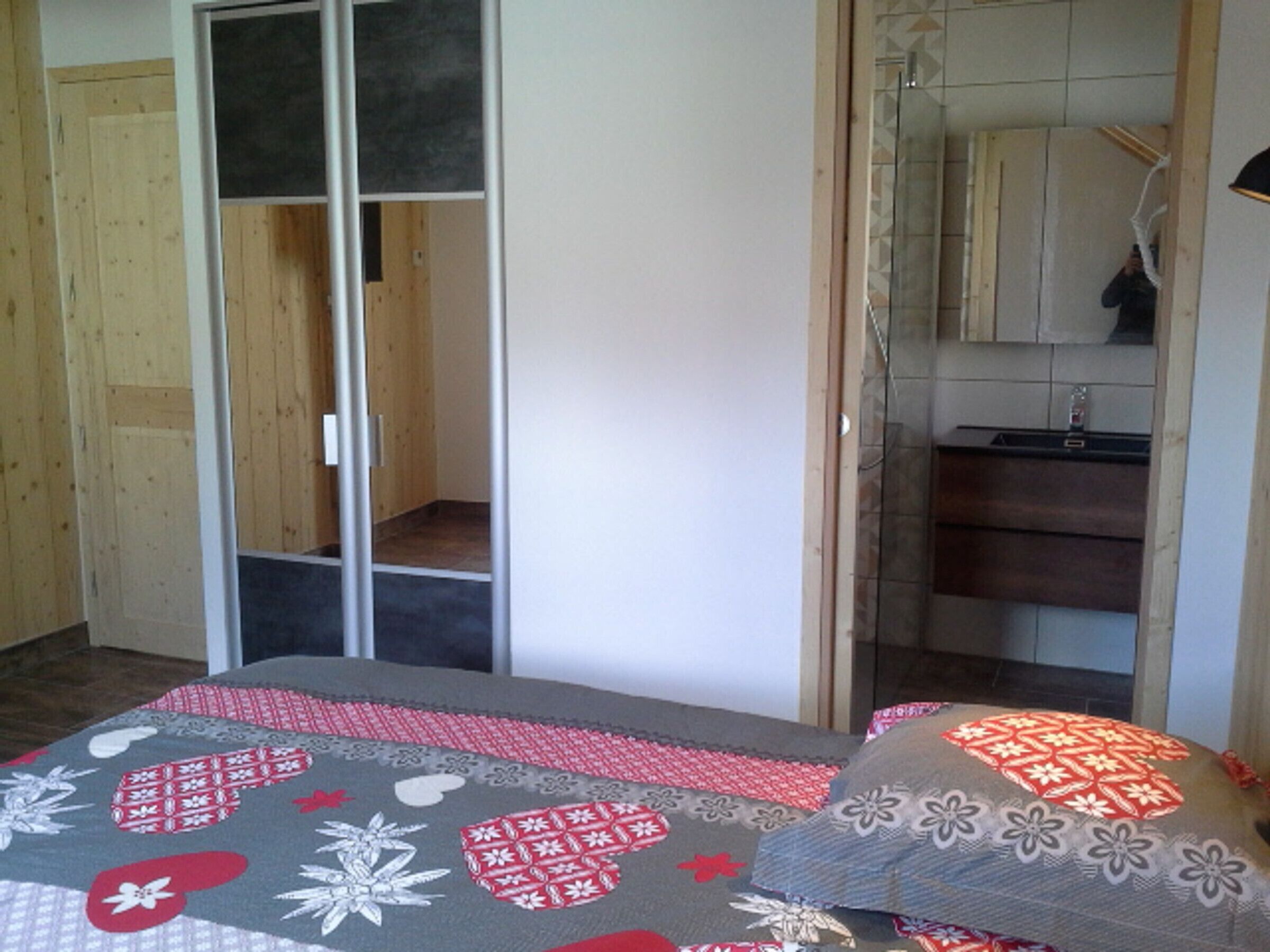 A bedroom with a bed, a wardrobe, and a bathroom visible through an open door.