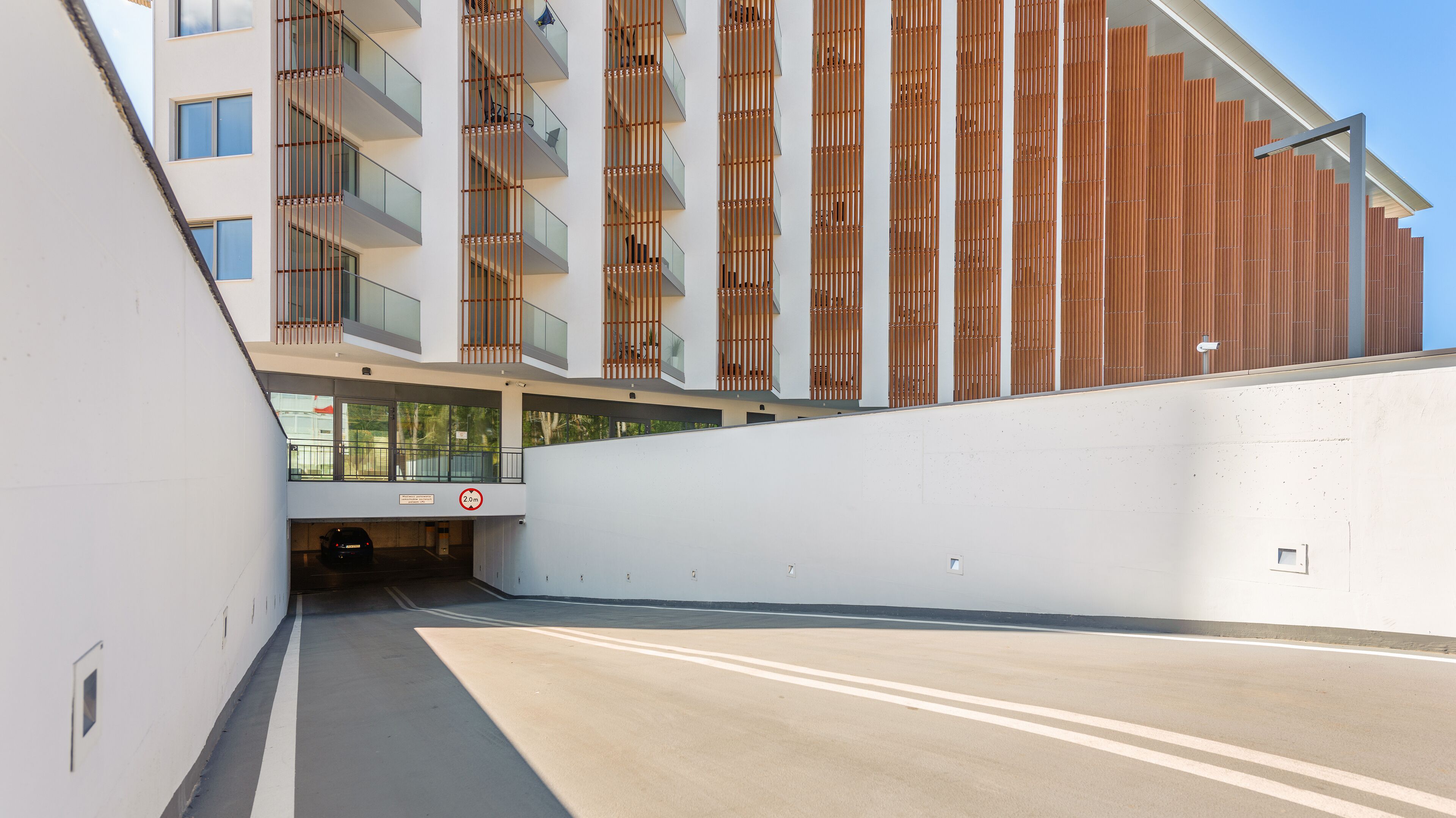 A modern building with a white facade and wooden slats on the upper floors.