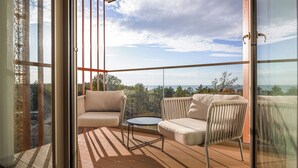A balcony with a sofa, a small table, and a chair, overlooking a scenic landscape. - Apartamenty Sun & Snow Qinea (Rewal)