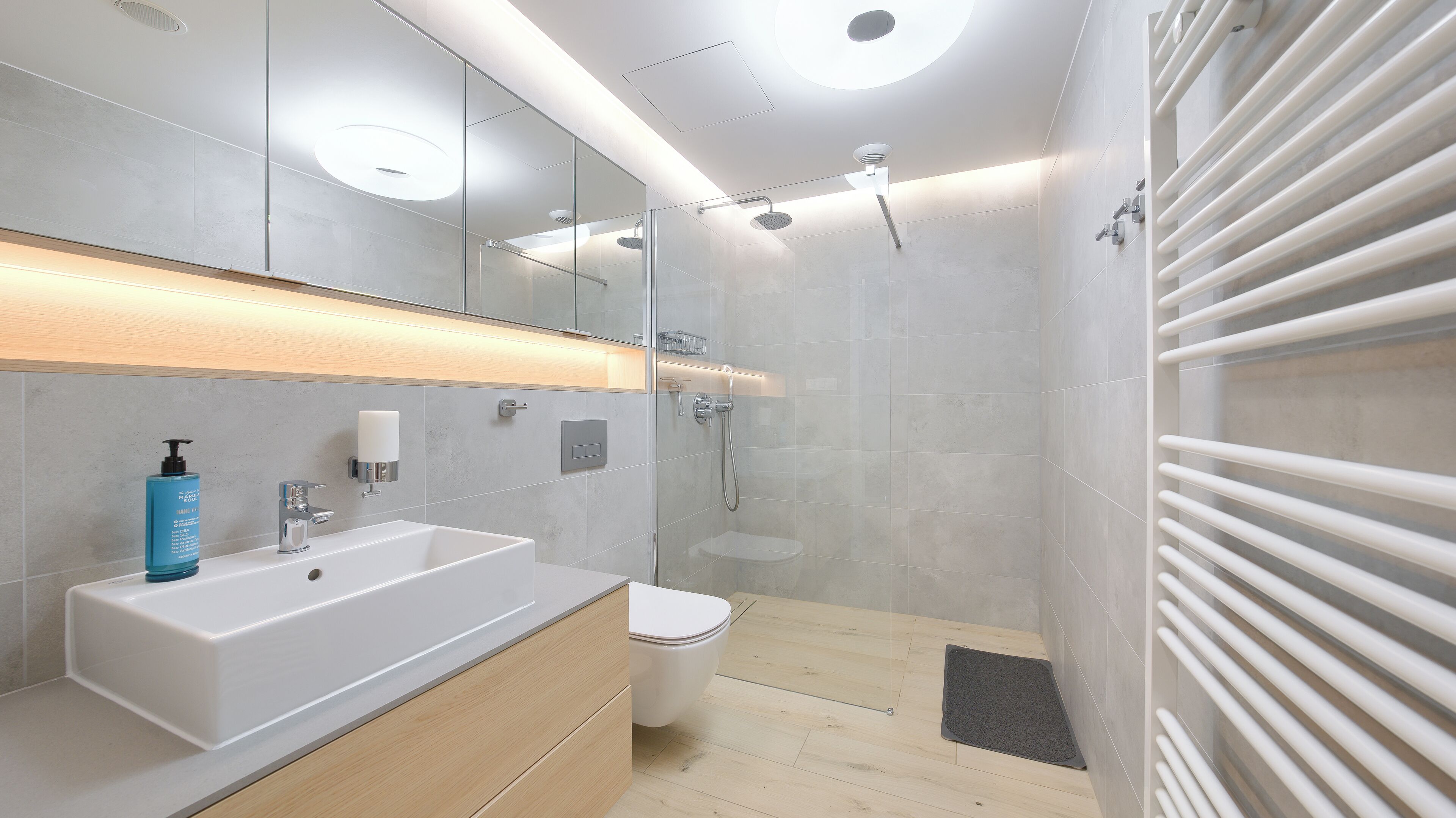 A modern bathroom with a large white sink, a glass shower enclosure, and a toilet.