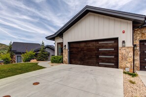 A modern two-story house with a large garage, stone accents, and a well-maintained lawn.