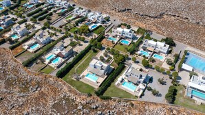 Vista aérea de un complejo turístico con varias edificaciones, piscinas y zonas ajardinadas.