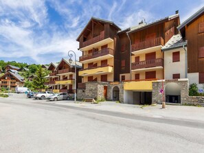 Ein mehrstöckiges Hotel mit Balkonen, einer Steinfassade und einem Parkplatz.