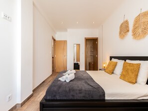 A modern hotel room with a large bed, a bedside table, and a wardrobe.