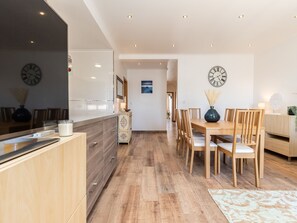 A modern kitchen with wooden cabinets, a large island, and two wall clocks.