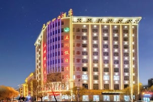 Un hotel de varios pisos con un cartel vertical llamativo en la fachada, numerosas ventanas y un techo plano.