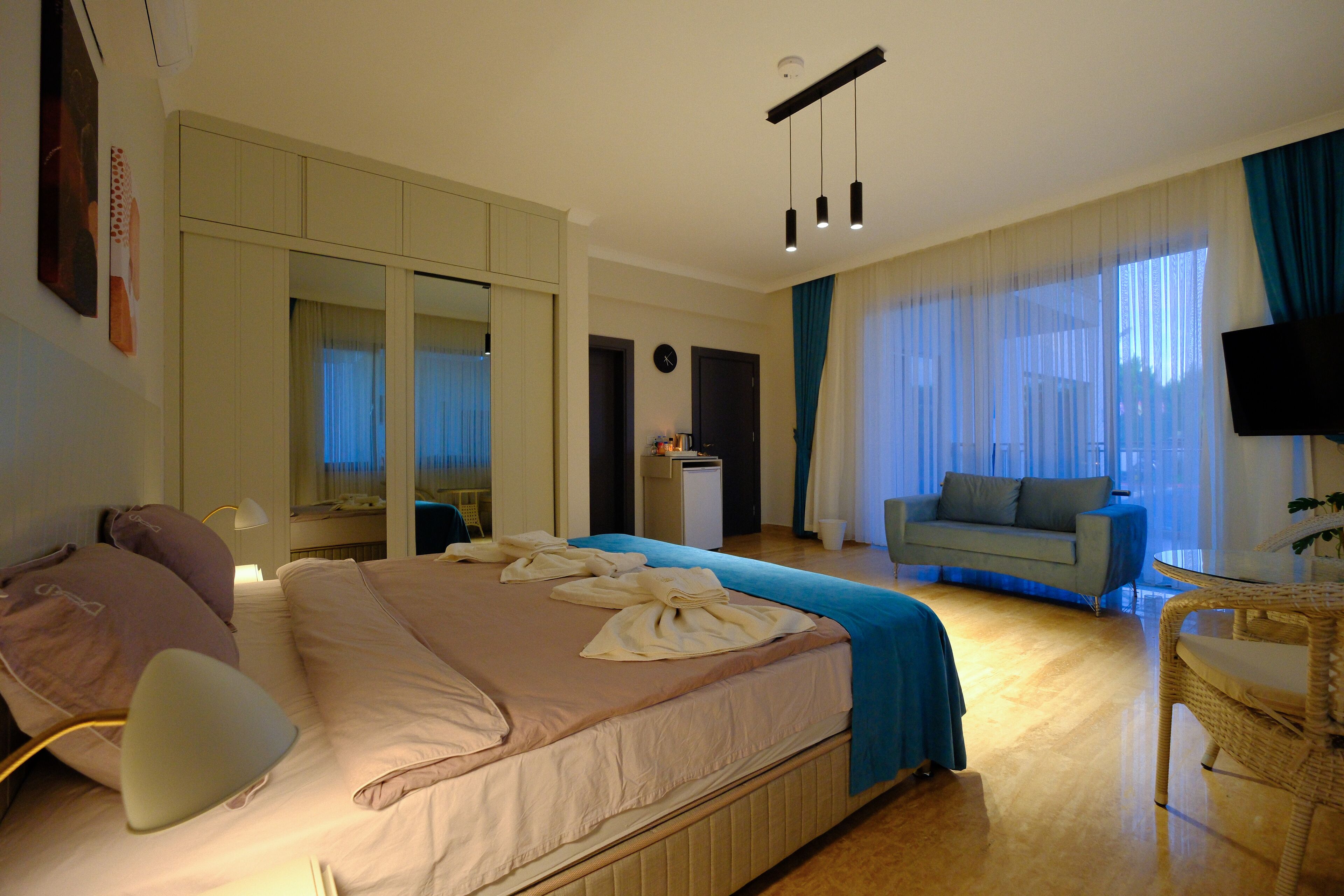 Una habitación de hotel con cama, sofá, televisión y escritorio.