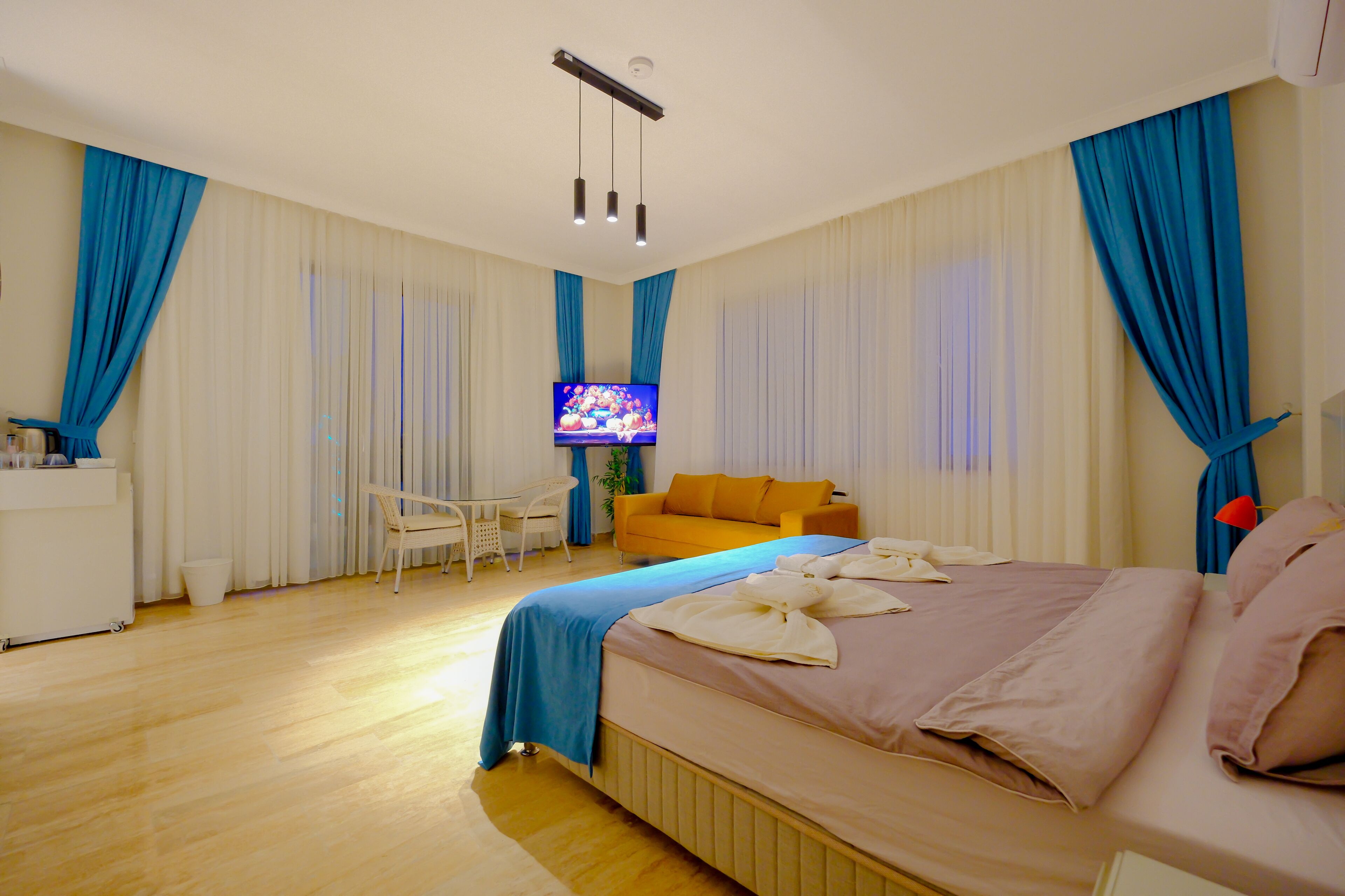 Camera d'albergo con un letto, una televisione, un divano, una scrivania e tende.
