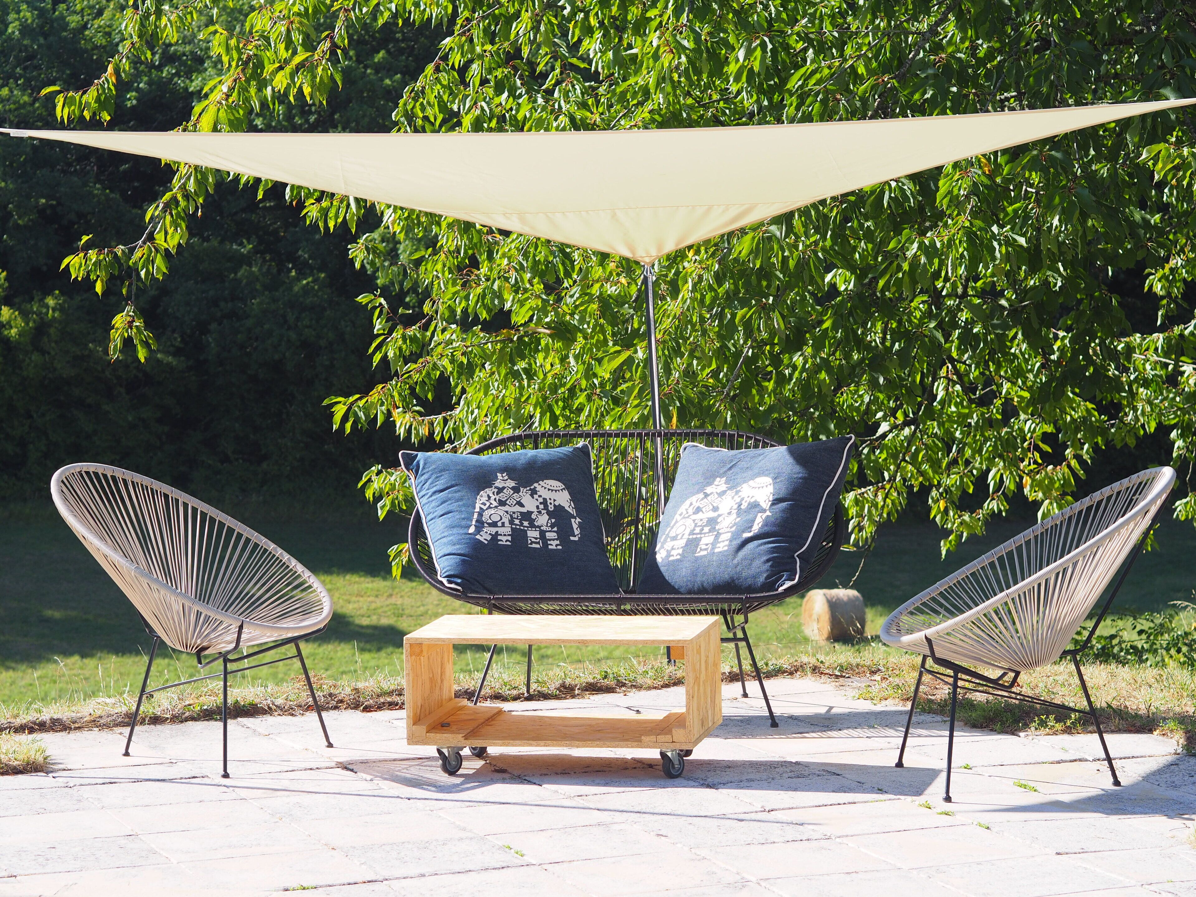 A patio with two wire-framed chairs, a wooden table, and a canopy.