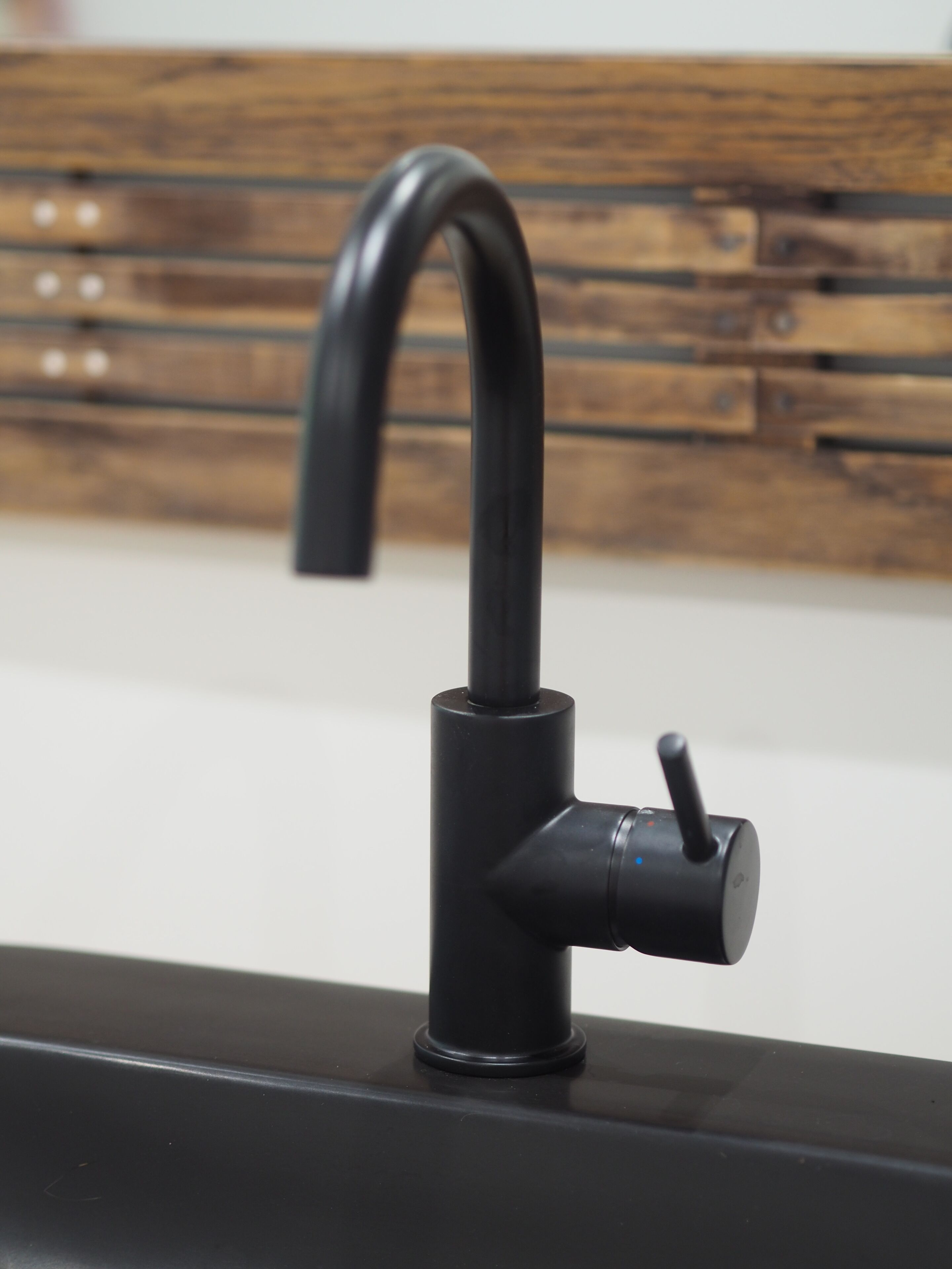 Eine moderne Küche mit einem schwarzen Wasserhahn auf einer weißen Arbeitsplatte.