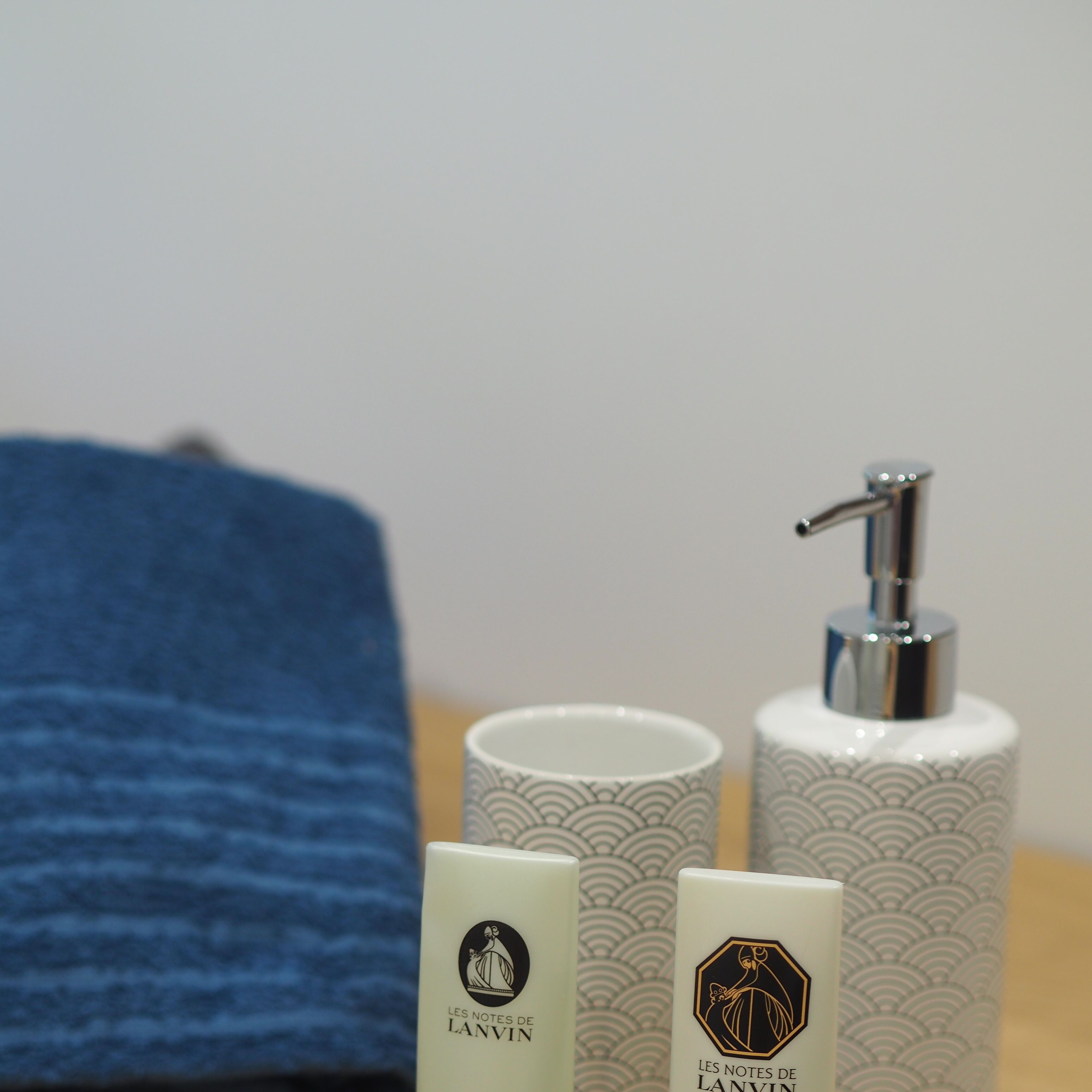 A bathroom with a blue towel, two toiletry bottles, and a soap dispenser.