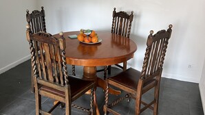 A round wooden dining table with four chairs, each featuring a twisted design. A plate of oranges is placed on the table. - Fellowes Garden (Peterborough)