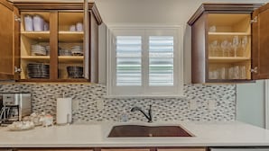 A kitchen with a white countertop, a sink, and wooden cabinets.
