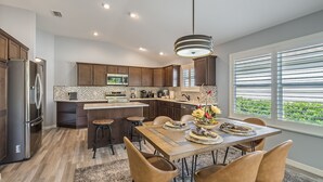 A modern kitchen with dark wood cabinets, stainless steel appliances, and a central island with stools.