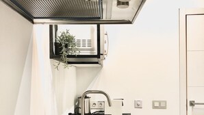 A compact kitchen with a stainless steel sink, a small countertop, and a built-in range hood. - Apartment 2 Rooms MURILLO (Madrid)