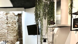 A modern kitchen with a stone wall, a dining area with a round table and chairs, and a black countertop with a sink. - Apartment 2 Rooms MURILLO (Madrid)
