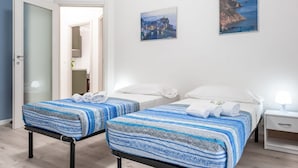 Ein Hotelzimmer mit zwei Betten, einem Nachttisch, einer Lampe und zwei gerahmten Bildern an der Wand.