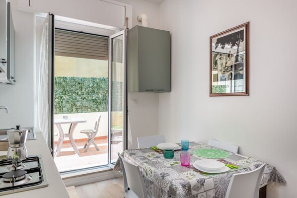 A kitchen with a gas stove, a table with a patterned tablecloth, and a dining area with chairs.