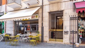 Ein Straßencafé mit Außenbereich, einer gut sichtbaren Schaufensterfront und einem Metallgitter.