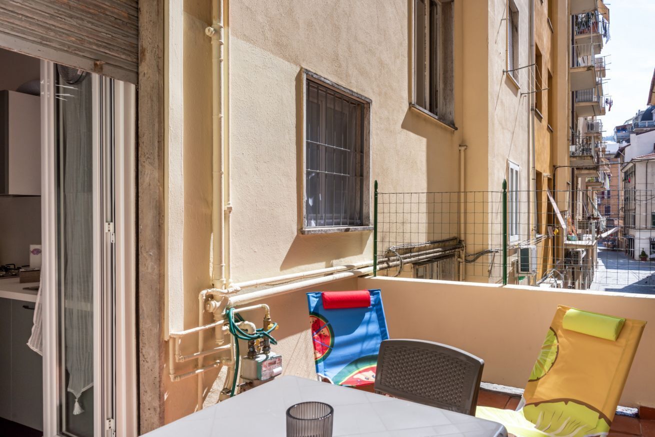 Un balcón con una mesa, sillas y vista a la calle.