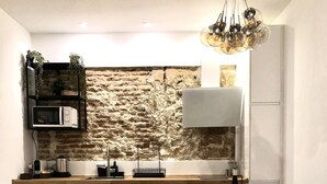 A modern kitchen with a stone wall backsplash, white cabinetry, and a round wooden dining table with white chairs.