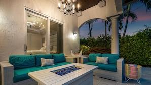 A modern outdoor seating area with a white table, teal sofas, and a decorative fire feature. - BY THE SEA VACATION VILLAS 5 STAR AQUABELLA  5/4 PRIVATE POOL WALK TO BEACH (Fort Lauderdale)