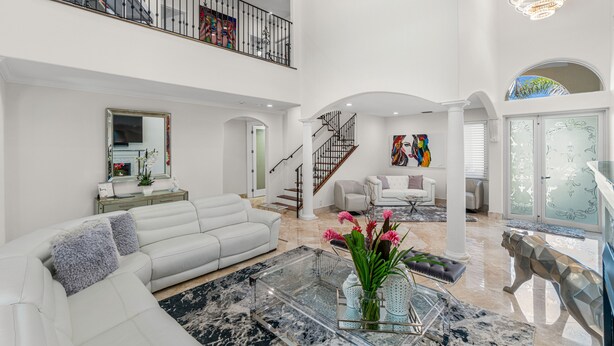 A spacious living area with a white sofa, a glass coffee table, and a decorative sculpture. - BY THE SEA VACATION VILLAS 5 STAR AQUABELLA  5/4 PRIVATE POOL WALK TO BEACH (Fort Lauderdale)