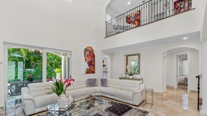 A spacious living room with a large sectional sofa, a glass coffee table, and a black and white rug. - BY THE SEA VACATION VILLAS 5 STAR AQUABELLA  5/4 PRIVATE POOL WALK TO BEACH (Fort Lauderdale)