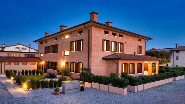A two-story brick house with a well-maintained garden and outdoor lighting. - Borgo Tabari Appartamento Renoir (Mussolente)
