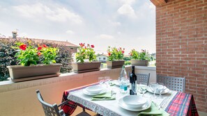 Eine Dachterrasse mit Essbereich, Topfpflanzen und freiem Blick auf die umliegende Nachbarschaft.