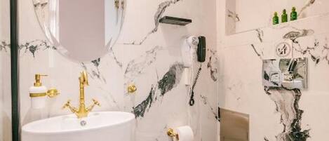 Une salle de bain avec un grand lavabo blanc, des robinets dorés et un mur décoré d’un motif imitant le marbre.