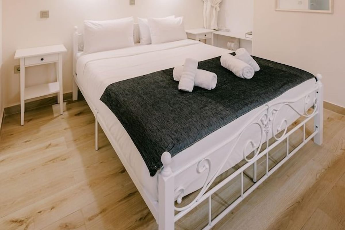 A hotel room with a bed, bedside table, and a mirror.