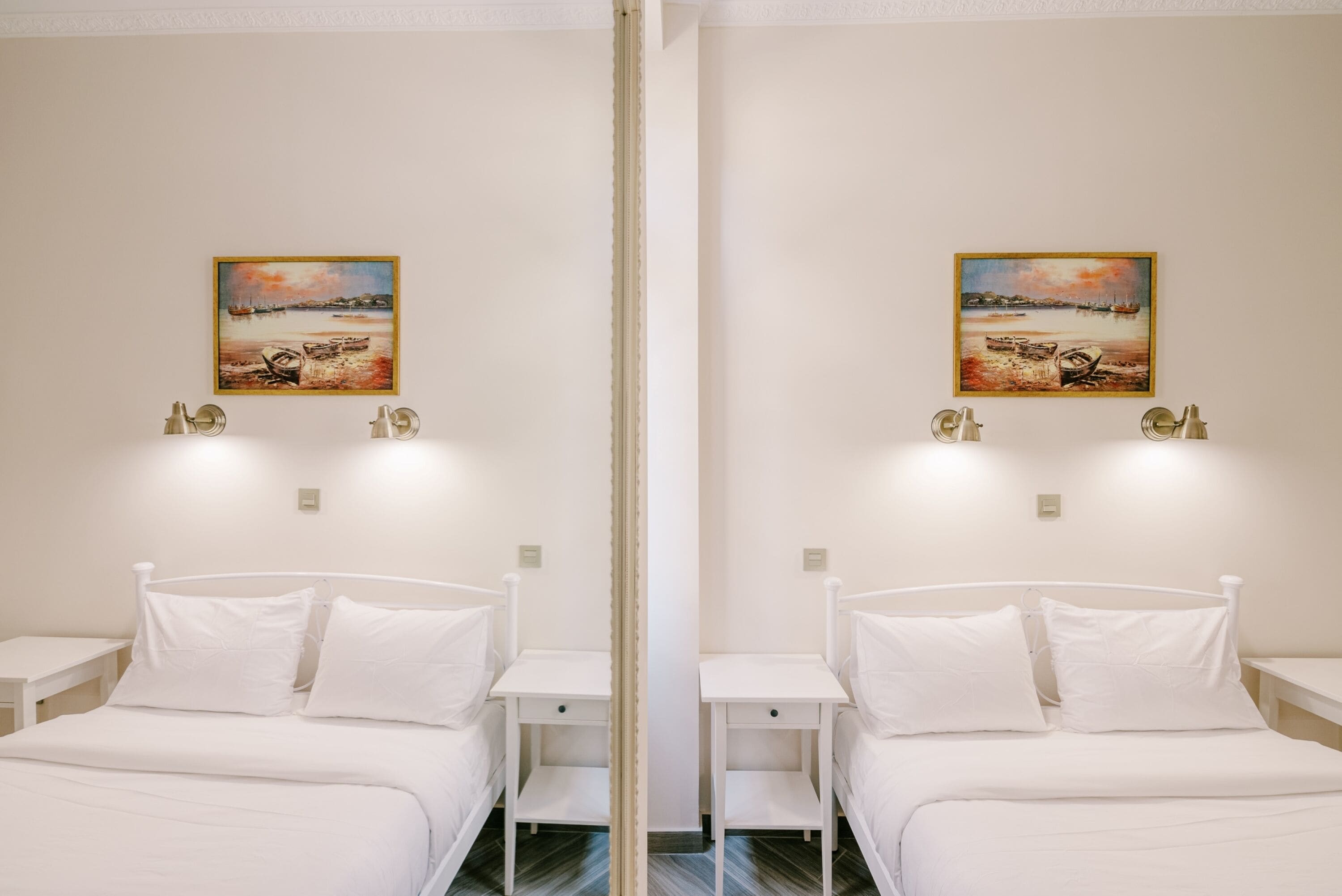 A mirrored room with two beds, nightstands, and wall-mounted lamps.