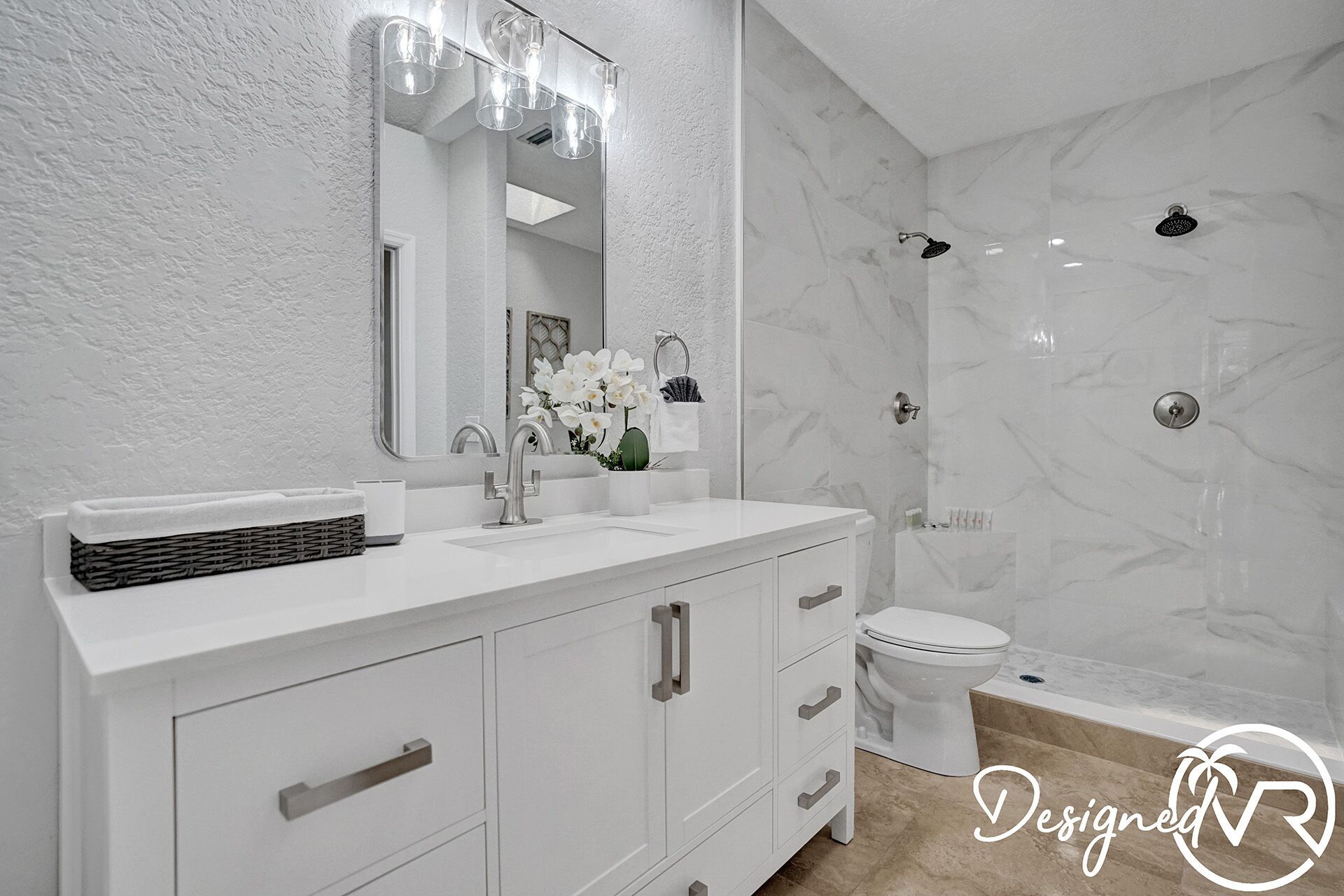 A modern bathroom with a white vanity, a large mirror, a shower with a glass door, and a toilet.