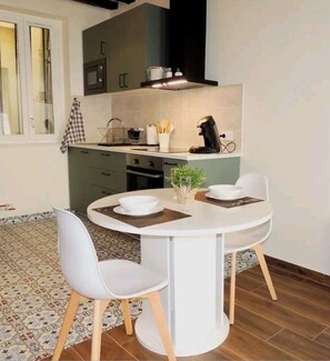 Modern kitchen with oven, microwave, and stainless steel range hood, featuring a central island and dining area with two chairs.
