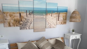 Un dormitorio con una cama grande, una mesita de noche y un cuadro colgado en la pared que representa una playa.