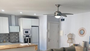 Una sala de estar moderna con sofá, una mesa de comedor y una cocina al fondo.