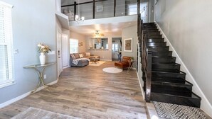 Een ruime woonkamer met een trap, houten vloer en moderne meubels.