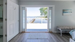Een kamer met een grote schuifdeur die uitkomt op een balkon met uitzicht op zee en een trap.