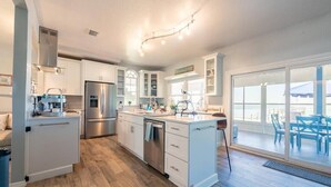 Een moderne keuken met witte kasten, roestvrijstalen apparatuur en een groot eiland.
