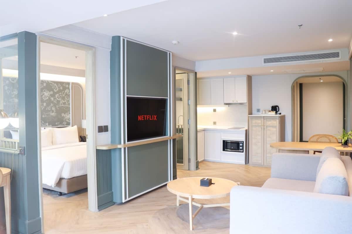 Une chambre d’hôtel moderne équipée d’un lit, d’un écran de télévision affichant « NETFLIX », d’un coin repas et d’une kitchenette.