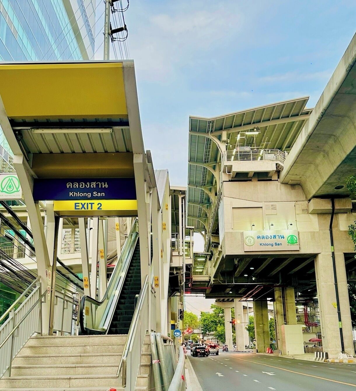 An urban setting with a sign for 'Khlong San' and 'EXIT 2'.