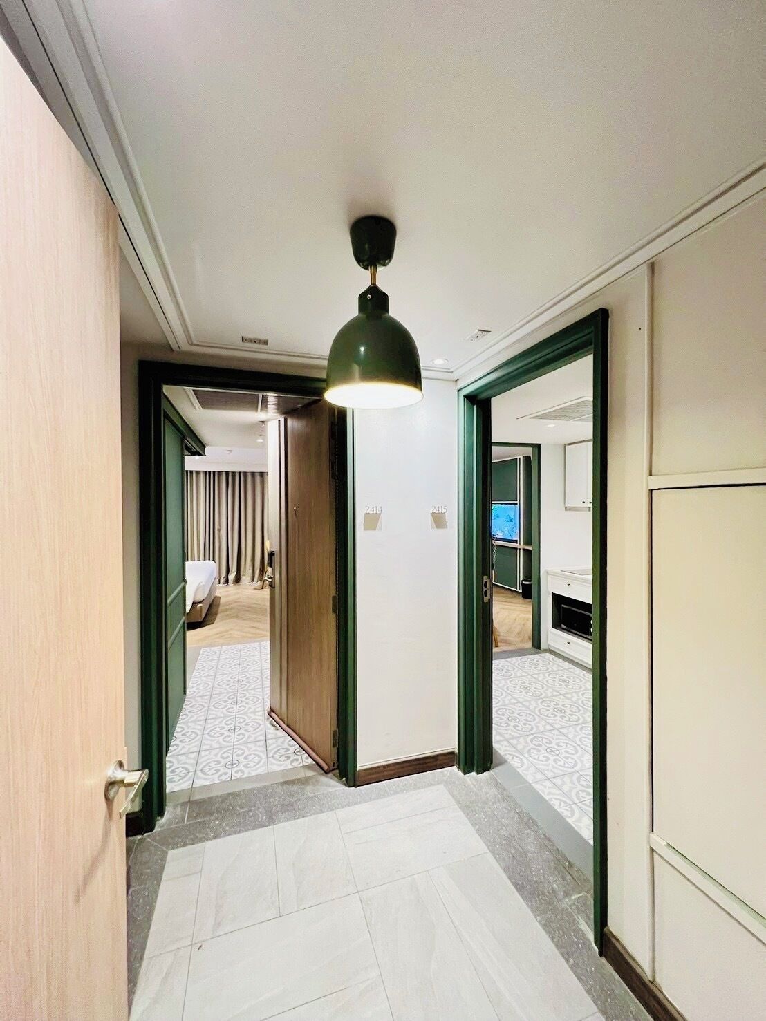 A hotel hallway with a modern design, featuring a large mirror, a wooden door, and a patterned floor.