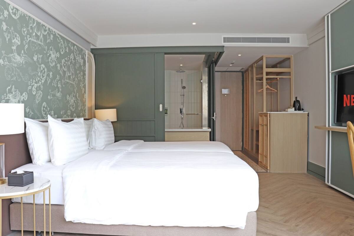 A hotel room with a large bed, a bedside table, a TV, and a wardrobe.