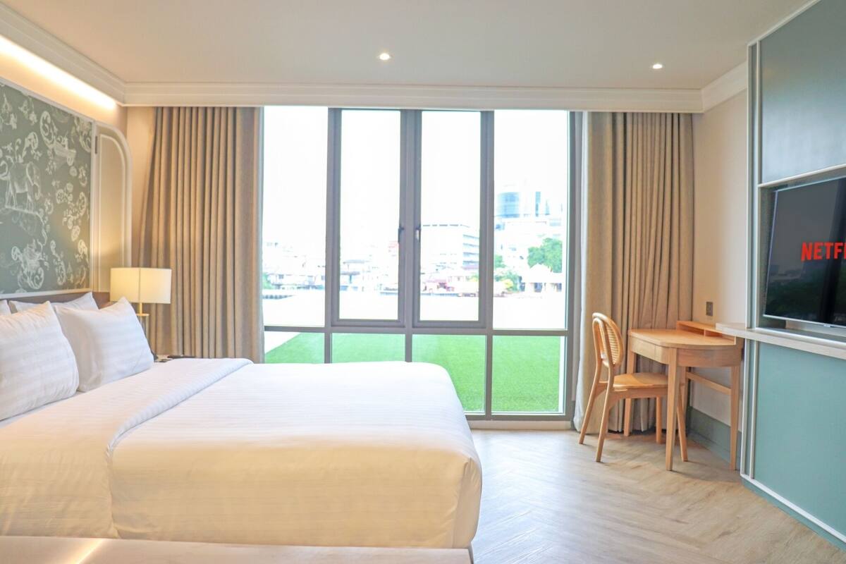 A hotel room with a large bed, a desk, and a TV.
