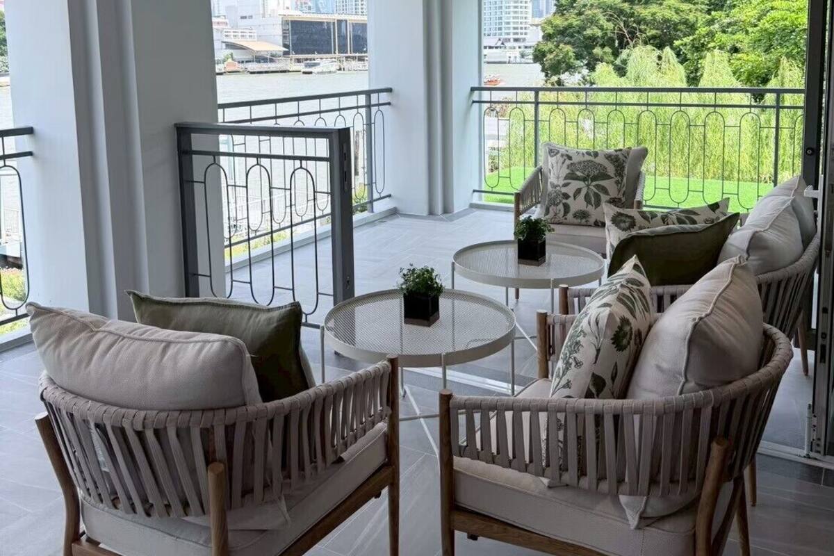 A balcony with wicker chairs, a small round table, and a view of the cityscape.